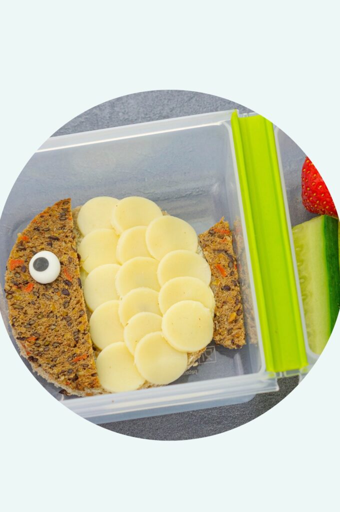 Gesundes Pausenbrot für Kinder: Kugelfisch-Käsebrot, dazu Gurkensticks und eine Erdbeere