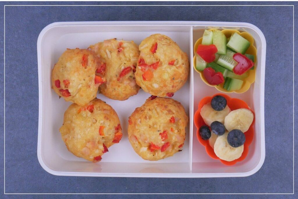 Lunchbox mit Pizzabällchen, Knabber Gemüse und Obst für Kinder oder Essen zum Mitnehmen für die Arbeit