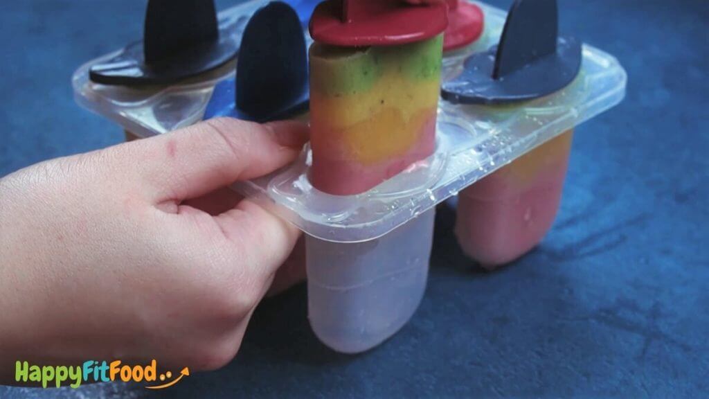 Regenbogen Popsicles nach dem Gefrieren am Stiel entnehmen